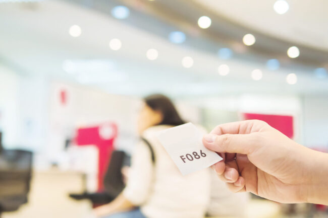 Man is holding queue card while waiting in the modern reception area