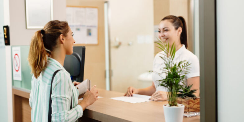 Happy woman talking to a receptionist while arriving at the spa.