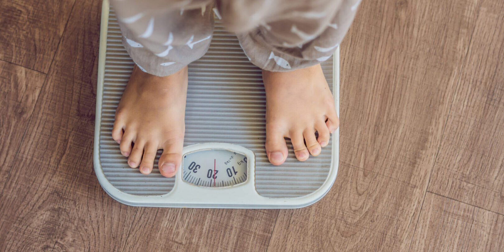 The boy stands on the scales to find out his weight